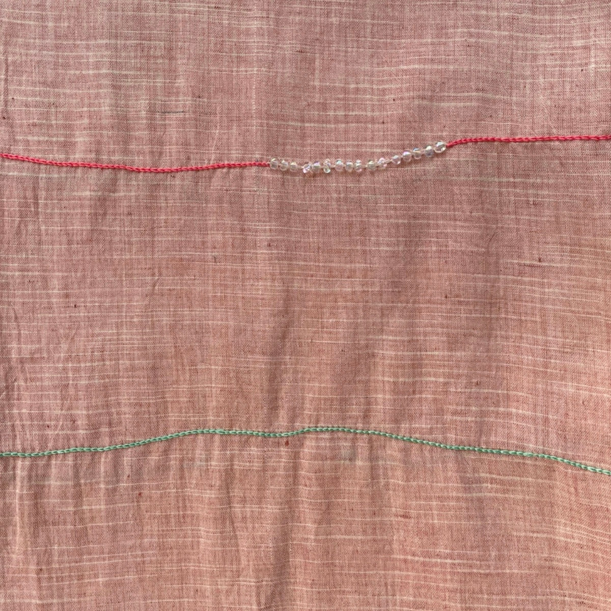 Close-up of embroidered linen scarf texture with subtle beadwork