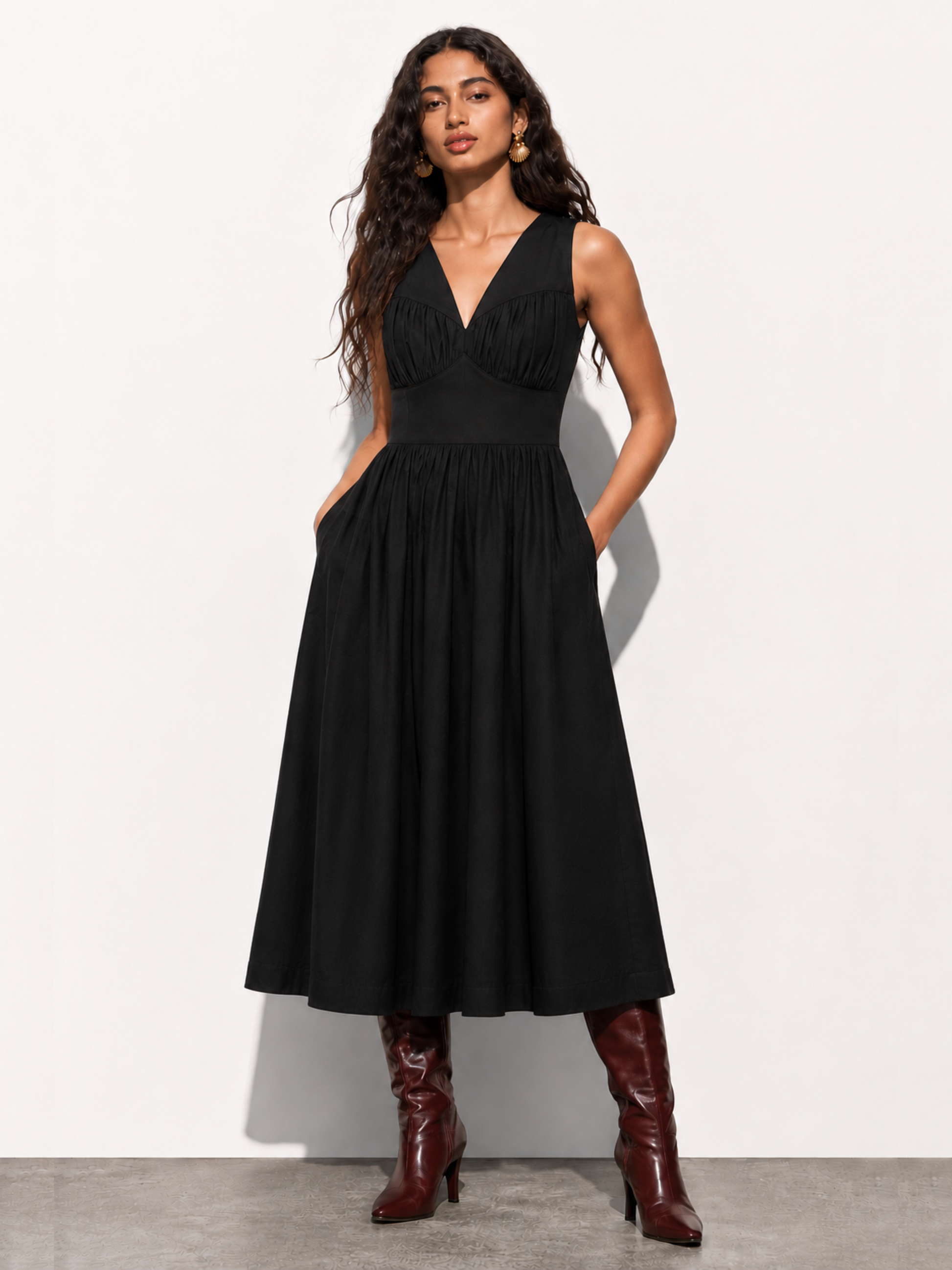Woman wearing a black dress with red boots against a white background